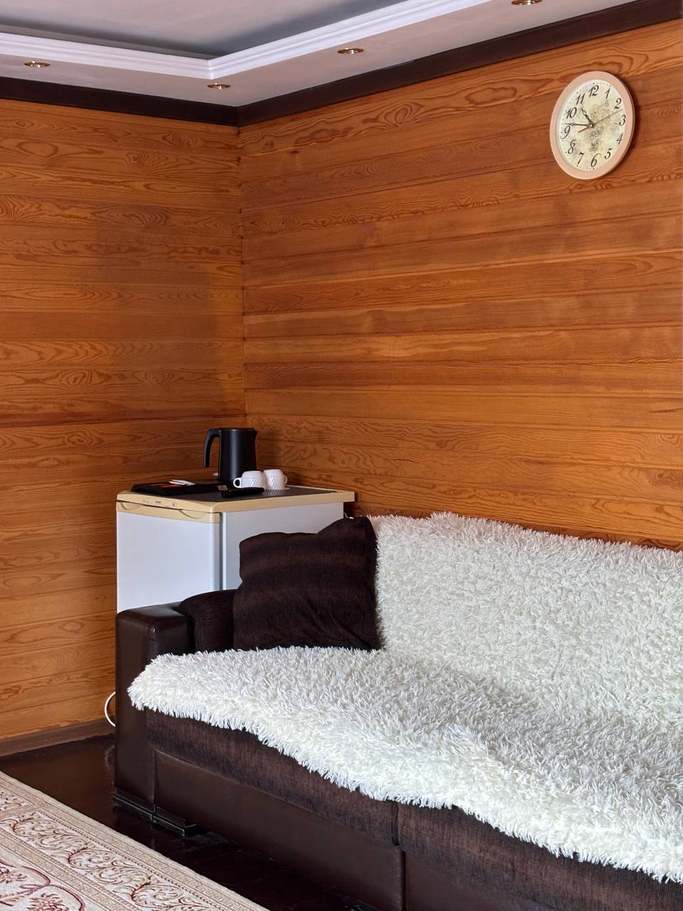 Уютный уголок номера с диваном и холодильником.
